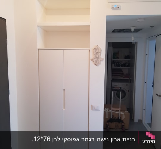 ארון לבן עם דלתות סגורות ומדפים מעליו